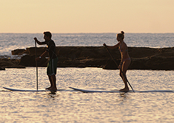Två killar utövar paddle surf vid Las Canteras