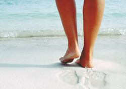 Några fötter i sanden på stranden