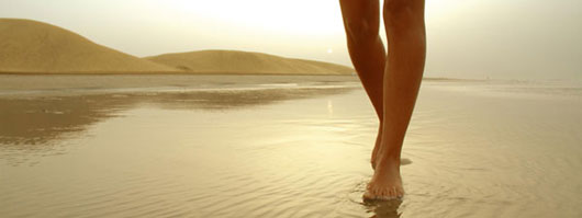 Una ragazza passeggia lungo la riva della Playa de Maspalomas