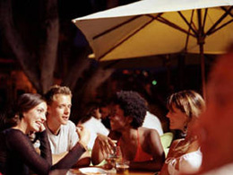 A group of friends drinking something on a terrace bar at night