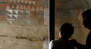 Två besökare betraktar målningarna i Cueva Pintada de Gáldar