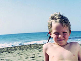 Frohes Kind am Strand von Maspalomas, im Hintergrund das Meer