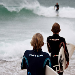 Two youngsters make their way into the sea with surf boards under their arms