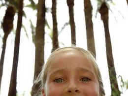 A girl photographed against a background of palm trees