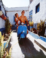 Couple riding along a typical Agaete street on a motorbike