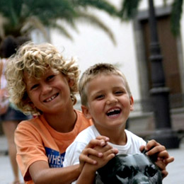 Two children smiling next to the sculptures in the Plaza Santa Ana