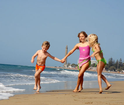 Tres niños juegan en la orilla de la playa de Maspalomas