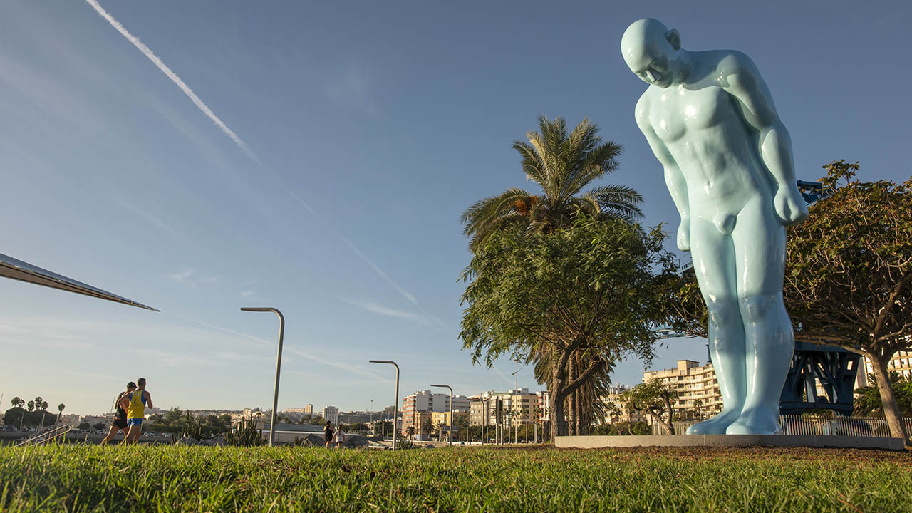 Two runners train next to the Greetingman sculpture