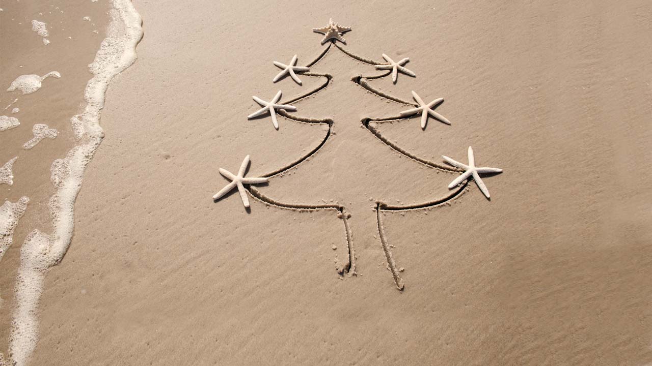 A Christmas tree drawn on the sand of the beach