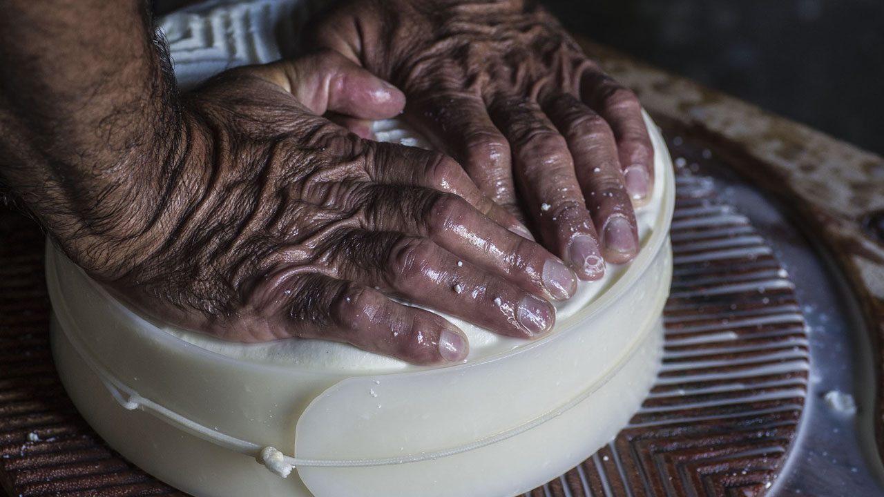 A man using his hands to make cheese