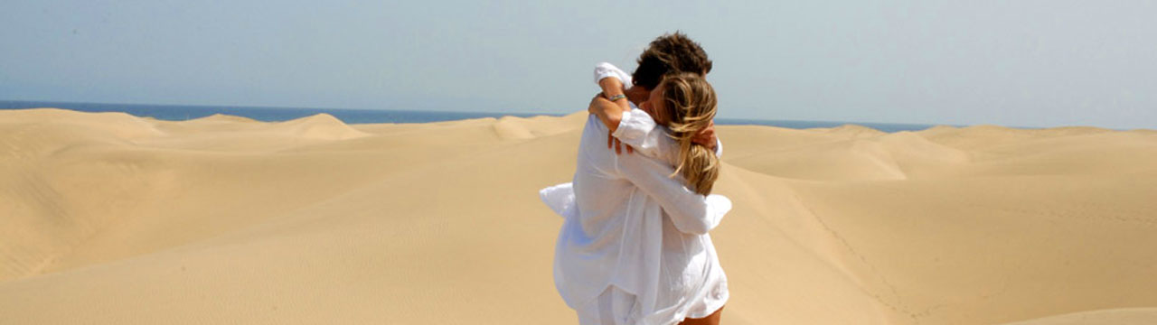 Una chica y un chico se abraza en las Dunas de Maspalomas