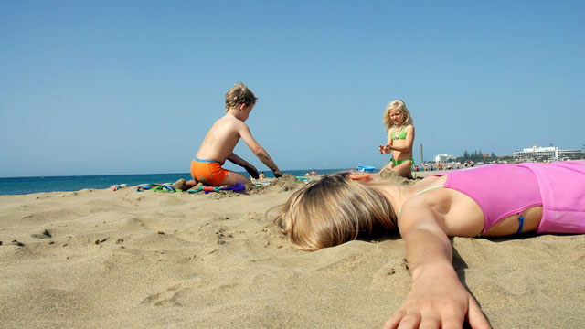 Tres niños juegan en la arena de la playa de Maspalomas