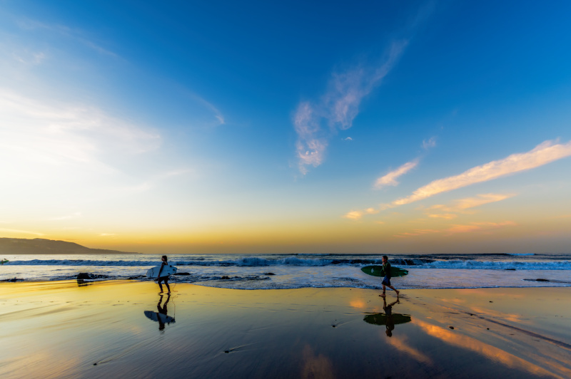 Foto de surfistas corriendo por la orilla de la playa