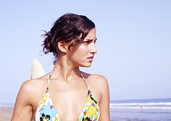 Una surfista mira las olas en la playa