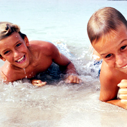 Two children smile happily while playing on the beach
