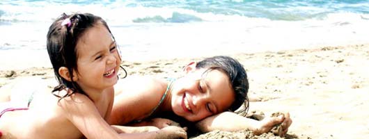 Two young girls playing and laughing on the beach at Las Canteras