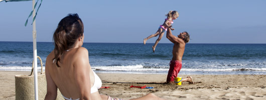 En pappa leker med sin dotter vid strandkanten
