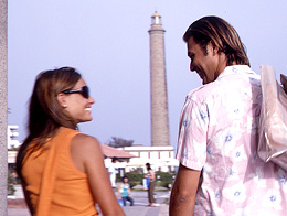 A couple chatting with the Lighthouse at Maspalomas in the background