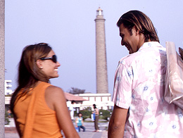 Un couple discute avec le phare de Maspalomas en fond