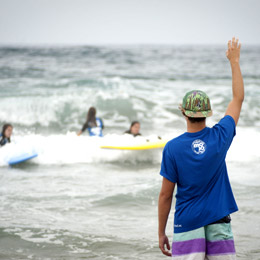 Several girl surfers follow their monitor’s instructions while catching waves