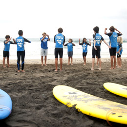 En grupp barn stretchar vid strandkanten