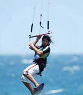 Kitesurfer fliegt im Manöver über das Wasser