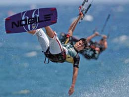 Two kids doing kitesurfing on the blue sea