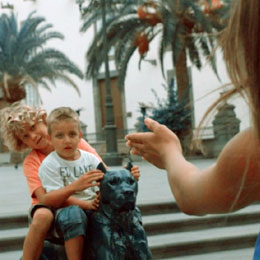 Deux enfants jouent assis sur les sculptures de la Place Santa Ana