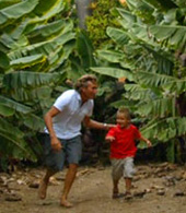 Vater und Sohn spielen in der Bananenplantage Verstecken