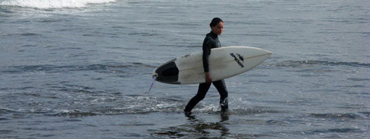 Kvinnlig surfare kommer upp ur vattnet vid Las Canteras