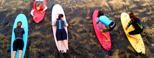 Un gruppo di ragazze impara a fare surf nella spiaggia di Las Canteras