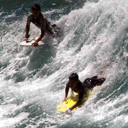 Zwei Jungen beim Bodyboarding am Strand von Las Canteras